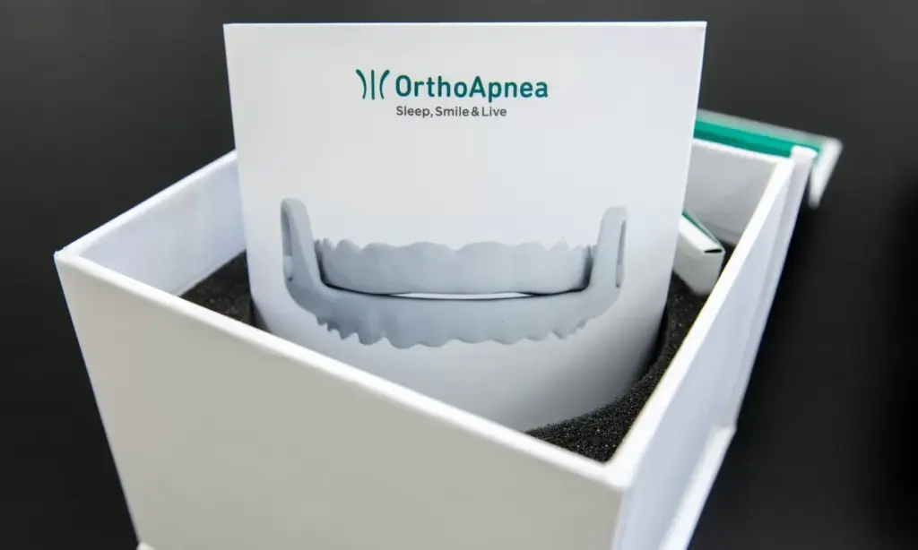 A custom-made OrthoApnea anti-snoring appliance displayed in its open presentation box