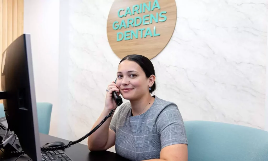 Receptionist taking a phone call at the front desk of Carina Gardens Dental in Carina, Brisbane