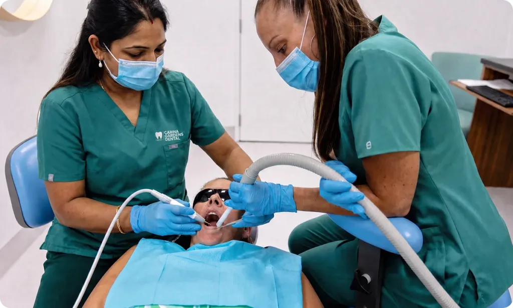 Dentist and dental assistant performing a check-up and clean for a patient at Carina Gardens Dental, Carina Brisbane