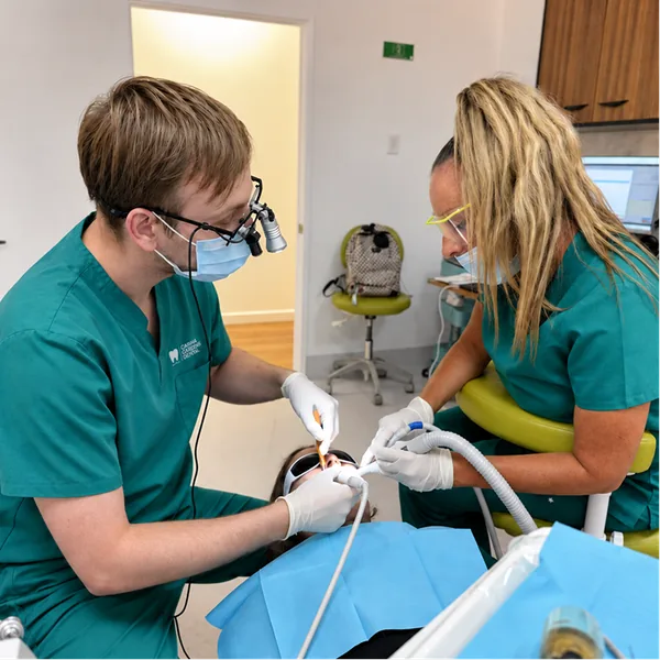Dentist wearing magnifying loupes treating a patient with a dental assistant during an emergency dental visit at Carina Gardens Dental, Carina Brisbane