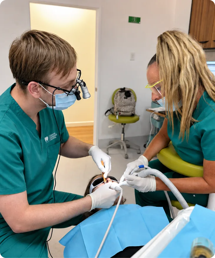 Dentist wearing magnifying loupes and a dental assistant examining a patient's teeth during a general examination at Carina Gardens Dental, Carina Brisbane