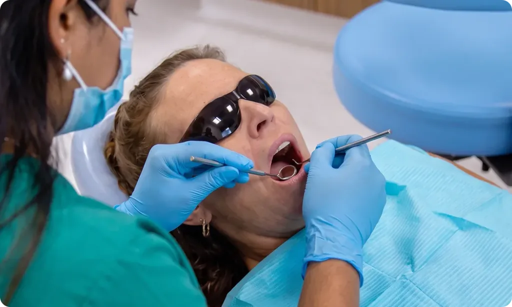 Dentist checking a patient's gums with a dental mirror and probe during a periodontal examination at Carina Gardens Dental, Carina Brisbane
