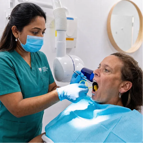 Dentist using a dental curing light on a patient's teeth during a preventive dental care appointment at Carina Gardens Dental, Carina Brisbane